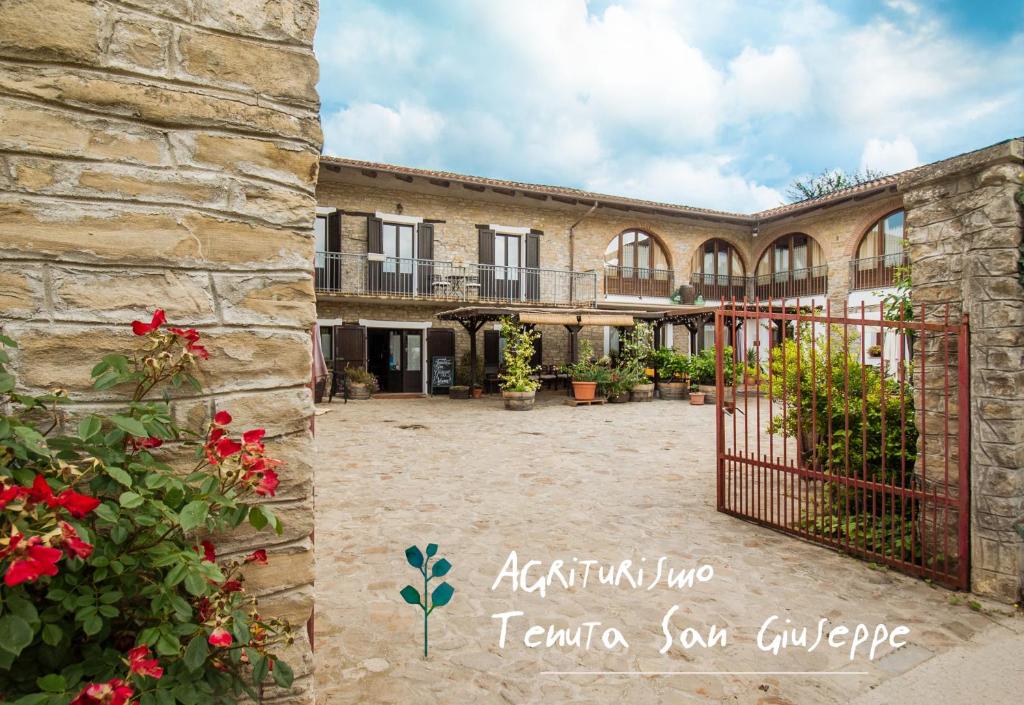 eine Außenansicht eines Gebäudes mit einem Tor und Blumen in der Unterkunft Agriturismo Tenuta San Giuseppe in Cossano Belbo