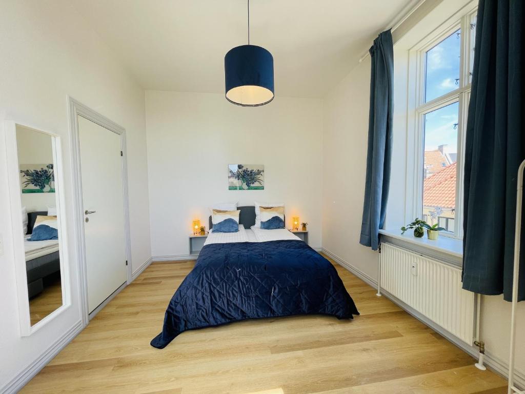 aday - Blue light suite apartment in the center of Hjorring في يورينغ: غرفة نوم بسرير ونافذة كبيرة
