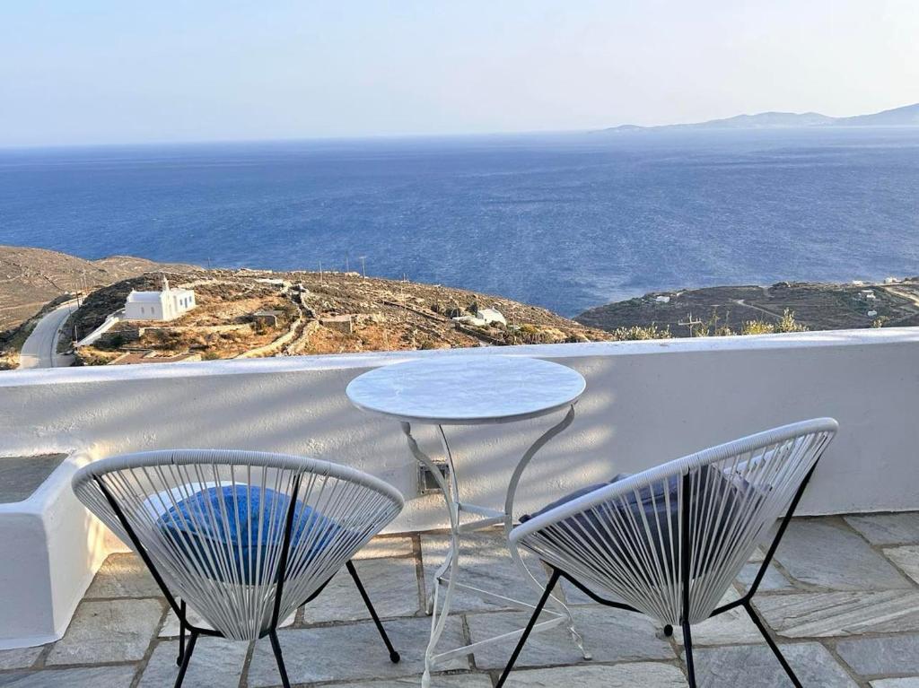 a table and chairs sitting on a balcony with the ocean at Sunny Stone Tinos House in Tinos