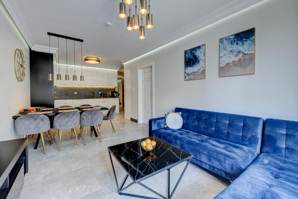 a living room with a blue couch and a table at MALAGA APARTAMENTY BALTICUS in Międzyzdroje