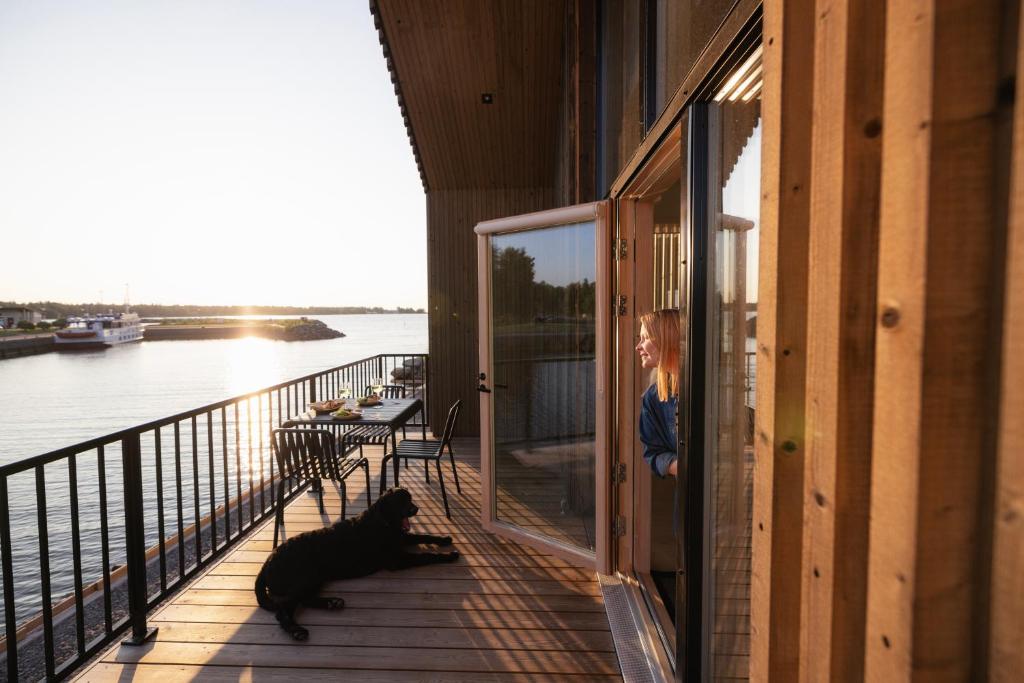 une femme debout sur un balcon avec un chien sur la terrasse couverte dans l'établissement Meriaitat, à Kokkola