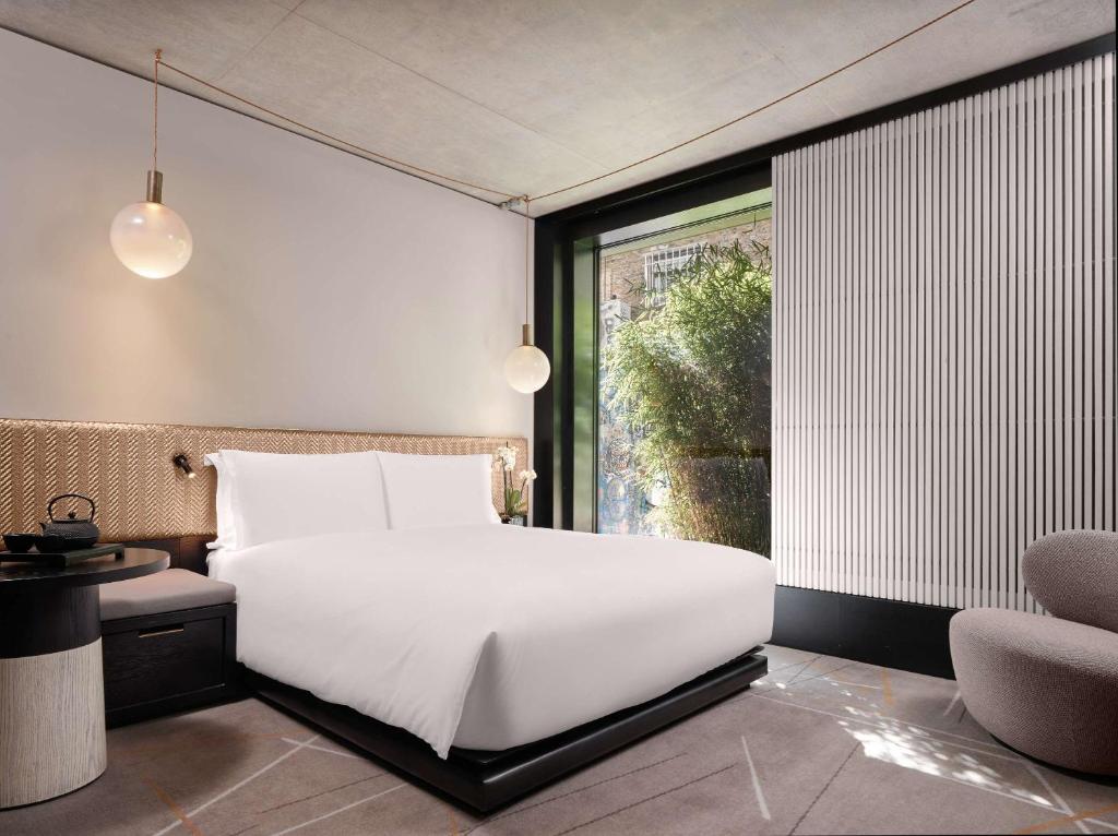 a bedroom with a large white bed and a window at Nobu Hotel London Shoreditch in London