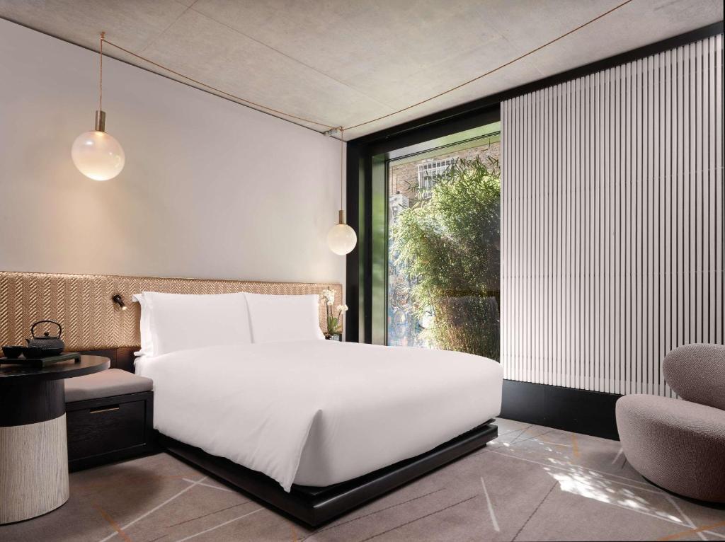 - une chambre avec un grand lit blanc et une fenêtre dans l'établissement Nobu Hotel London Shoreditch, à Londres