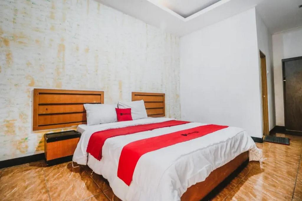 a bedroom with a large bed with a red and white blanket at RedDoorz Plus at Neo Asri Hotel Megamendung Puncak Bogor in Bogor