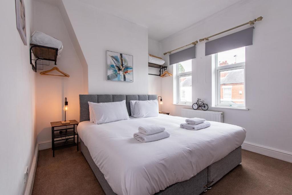 - une chambre avec un grand lit blanc et 2 serviettes dans l'établissement Lumley House - Delightful 2BR Terraced House near Birmingham, à Walsall