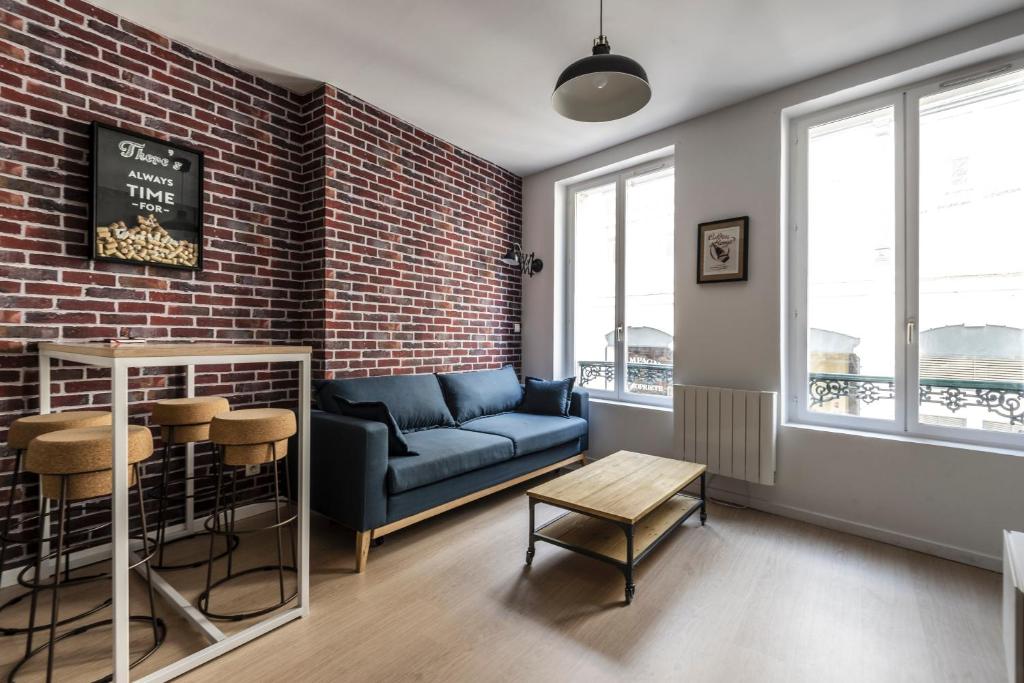 uma sala de estar com um sofá e uma parede de tijolos em Appartement Hyper Centre, Avenue de Champagne à 200 mètres em Épernay