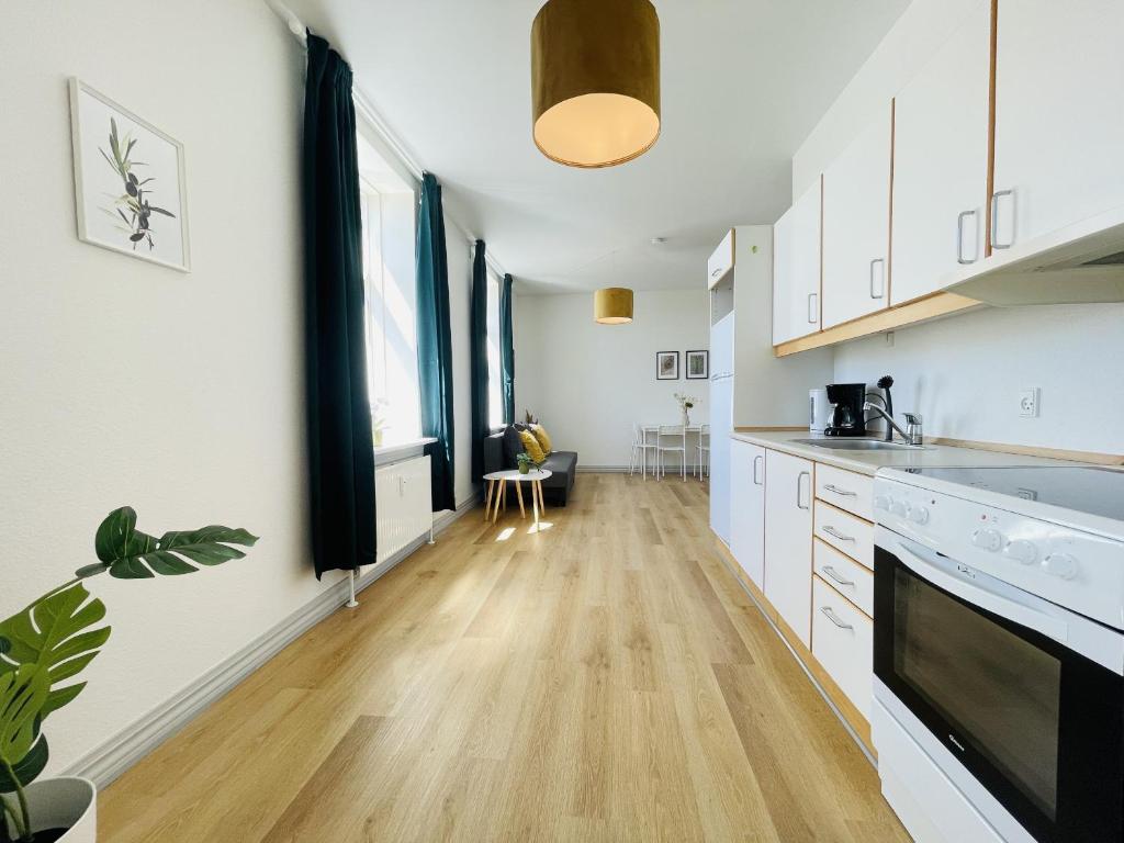 a kitchen with white cabinets and a wooden floor at aday - Green Light Apartment Suite in the center of Hjorring in Hjørring