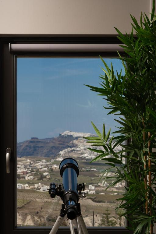 a camera in front of a window with a view at Apikia Santorini in Pirgos