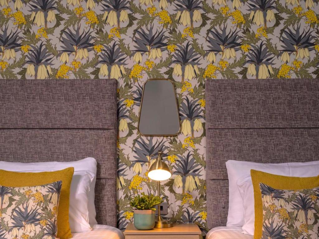 a bedroom with two beds and a floral wallpaper at Clifton Arms Hotel in Lytham St Annes