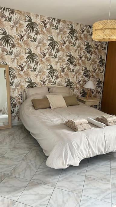 a bed in a bedroom with a wall with palm trees at Casa Ghjuvanna 2 chambres in Prunelli-di-Fiumorbo