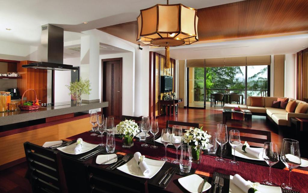 a dining room with a table and a living room at Mövenpick Resort Bangtao Beach Phuket in Bang Tao Beach