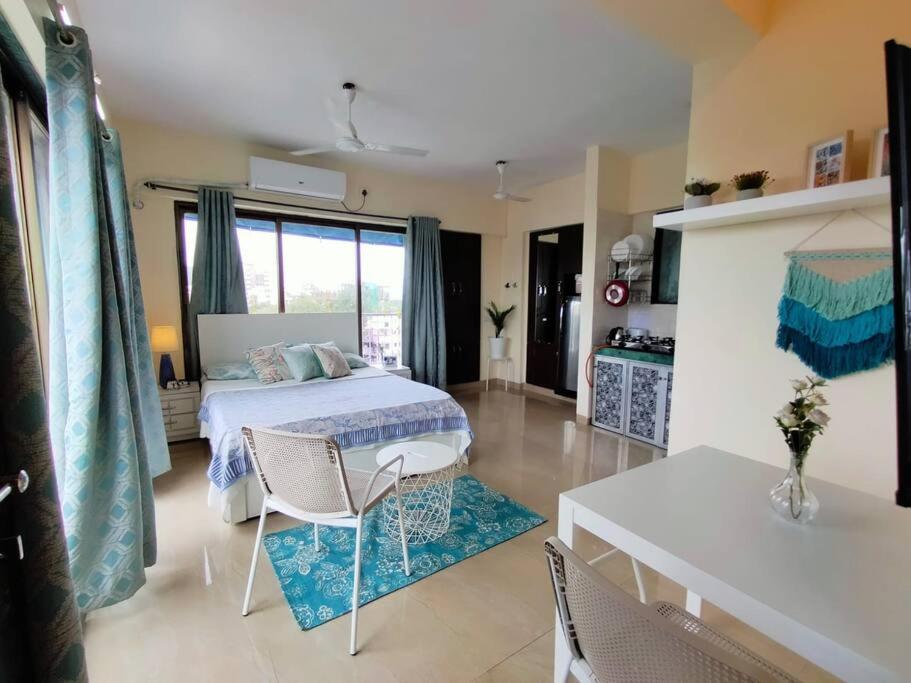 1 dormitorio con 1 cama, mesa y sillas en 6 - Studio Velankanni Heights, Behaind Nanavati Hospital, Vile Parle by Connekt Homes en Bombay