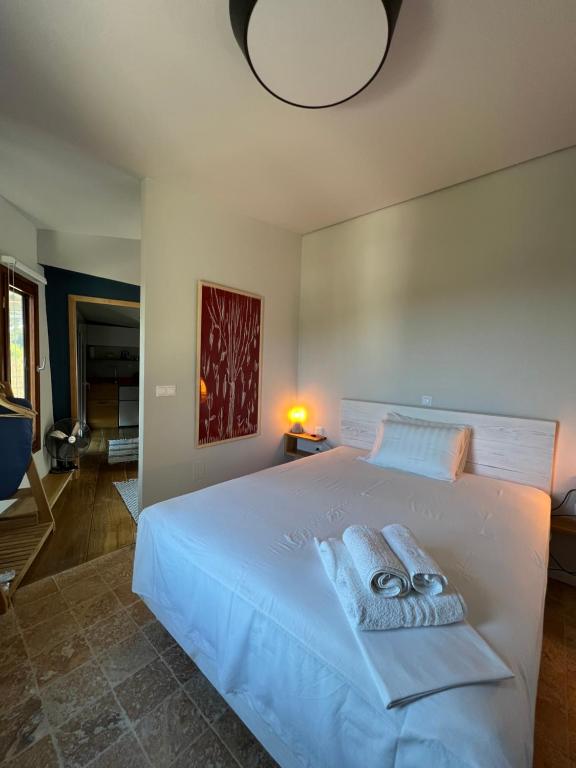 - une chambre avec un lit blanc et des serviettes dans l'établissement Corto, à Leucade