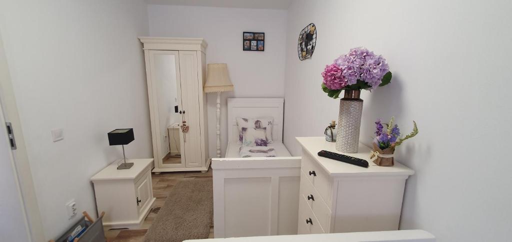 een witte badkamer met een vaas met bloemen op een toonbank bij Smiley Rezident in Sibiu
