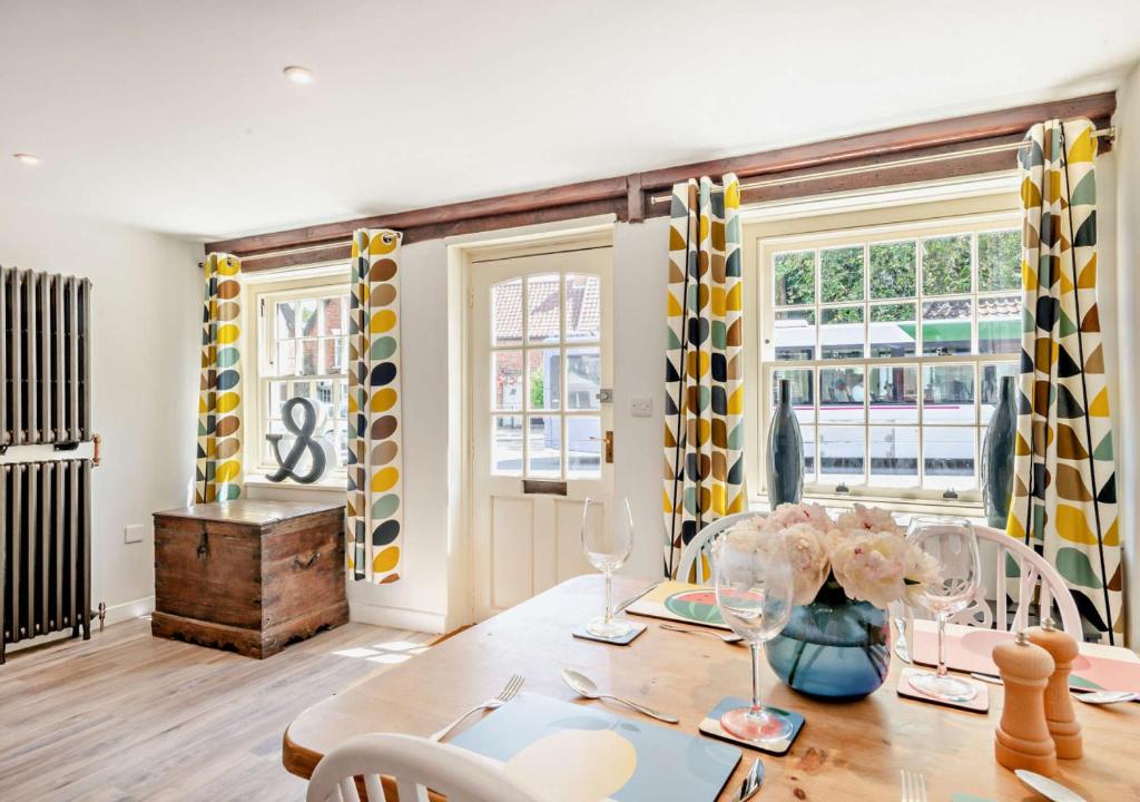 a dining room with a table and chairs and windows at Old Flint Bank Cottage in Harleston