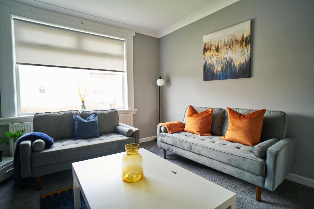 a living room with two couches and a table at West Apartment in Coatbridge