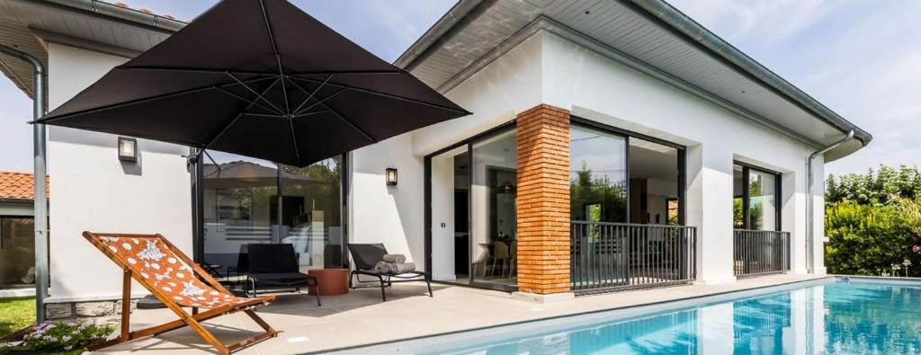 une maison avec une piscine et une terrasse avec un parasol dans l'établissement VILLA DU GOLF - Keyweek- Villa Biarritz with swimming pool, à Biarritz