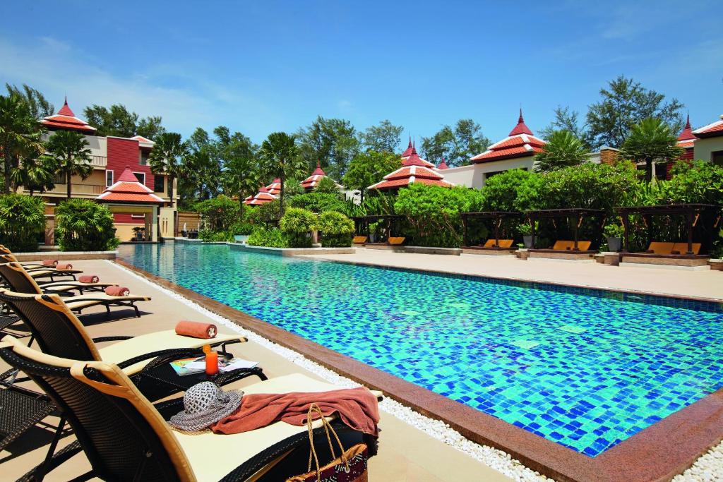 a row of chaise lounges by a pool at a resort at Mövenpick Resort Bangtao Beach Phuket in Bang Tao Beach
