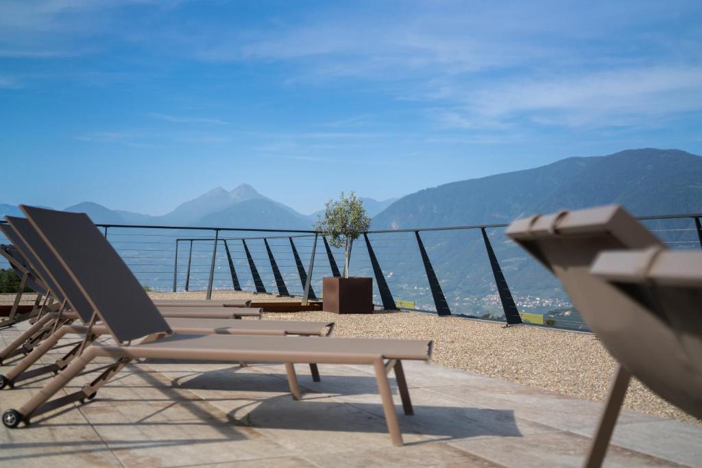 un grupo de sillones sentados en un balcón con vistas al agua en Oliven- & Genusshotel Hirzer, en Scena