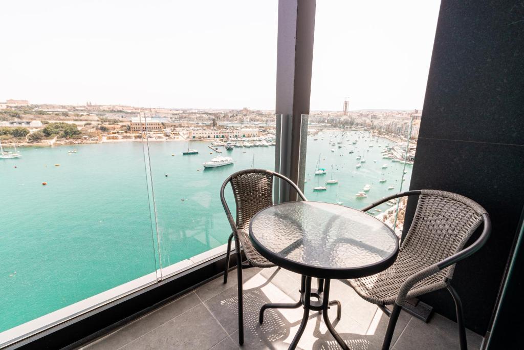 una mesa y sillas en un balcón con vistas al puerto en The Londoner Hotel Sliema, en Sliema