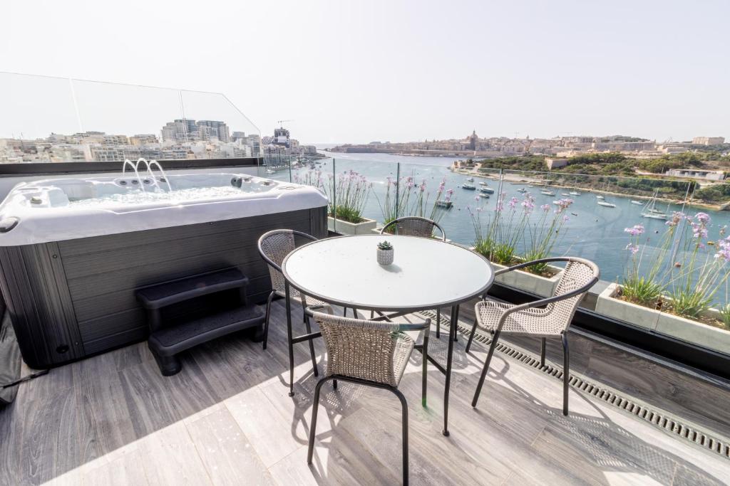 un balcon avec une baignoire, des tables et des chaises dans l'établissement The Londoner Hotel Sliema, à Sliema