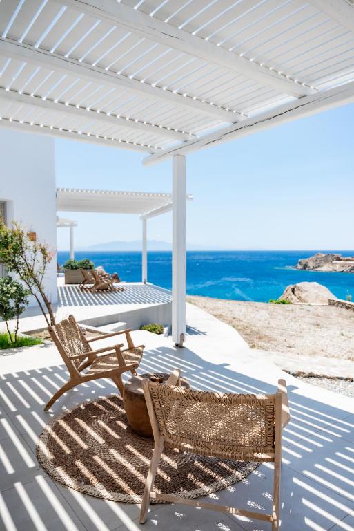 a patio with two chairs and a table and the ocean at Super Paradise Hotel in Super Paradise Beach