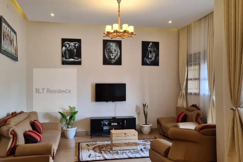 sala de estar con sofás y TV de pantalla plana. en BLT Residence - Kasese A serene and tranquil home, en Kasese