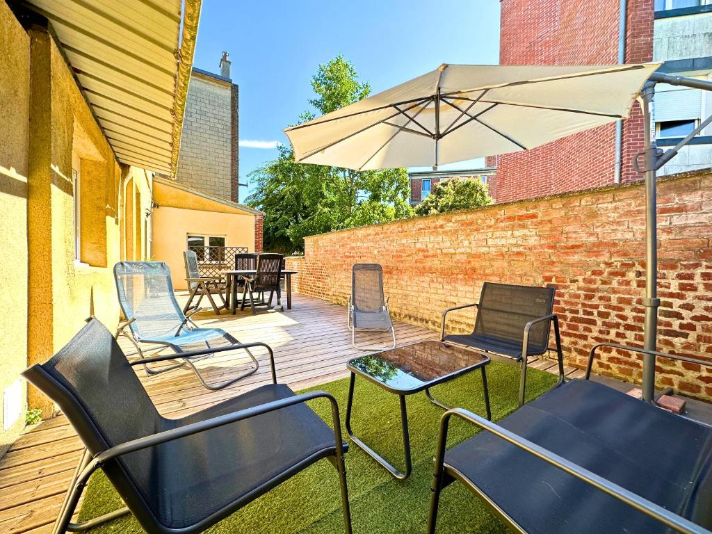 eine Holzterrasse mit Stühlen und einem Sonnenschirm in der Unterkunft Chill & Sun - Terrasse extérieure - Parking - Wifi - 4p in Amiens