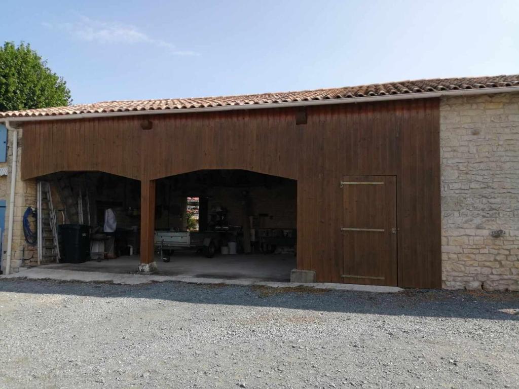 a large wooden barn with a large door at Gite Bin Benaise sans linge in Pamproux