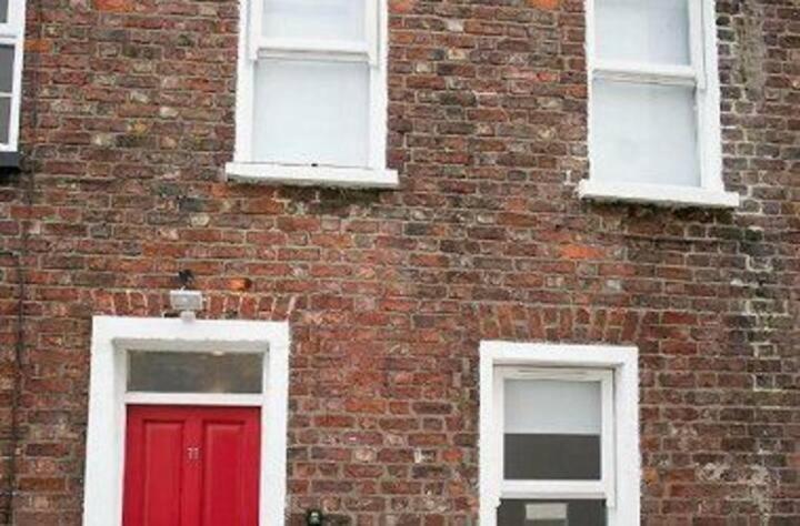 a brick building with a red door and three windows at AMAZING 3 BEDROOM HOME, PRIME BT1 POSTCODE AND CITY CENTRE LOCATION in Belfast