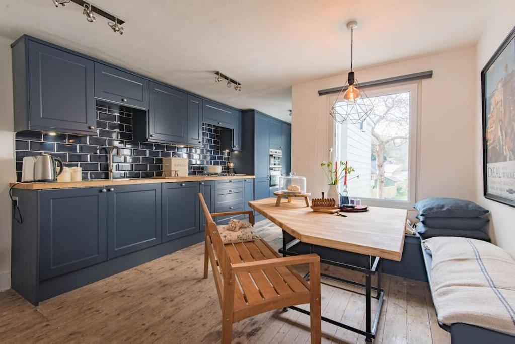 a kitchen with blue cabinets and a wooden table at Poppy Cottage in Kingsdown
