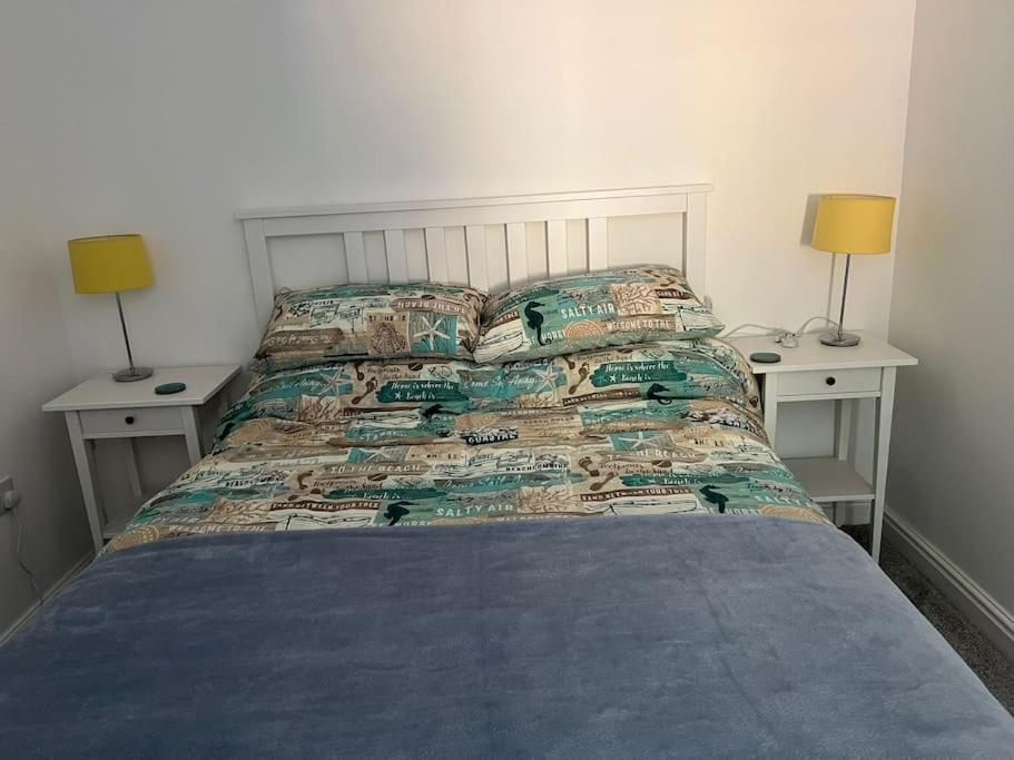 a bedroom with a bed with two nightstands and two lamps at El Sea House in Chapel Saint Leonards