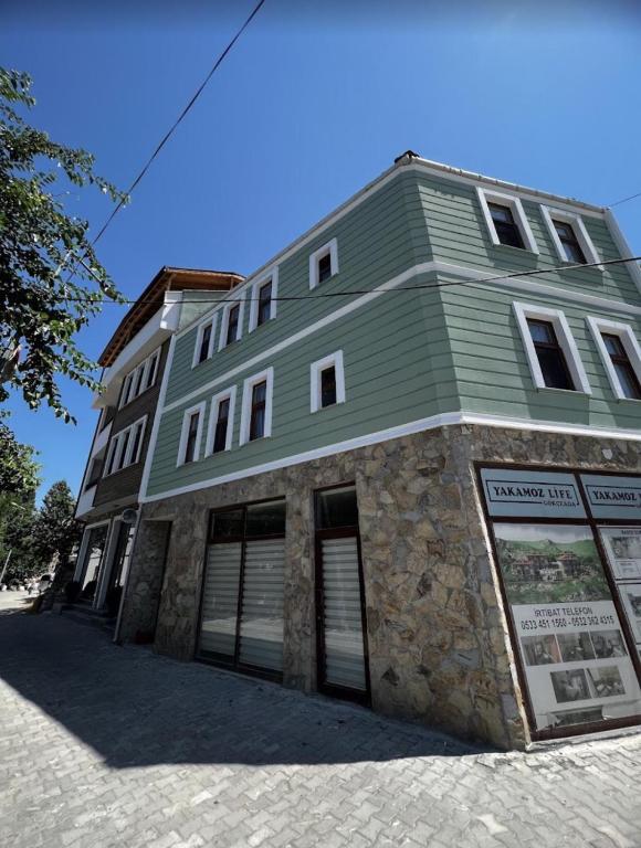 a stone building with a green roof on a street at Akar Butik Otel in Gokceada Town