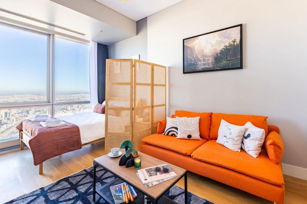 a living room with an orange couch and a bed at Studio Flat with Panoramic City View in Atasehir in Istanbul