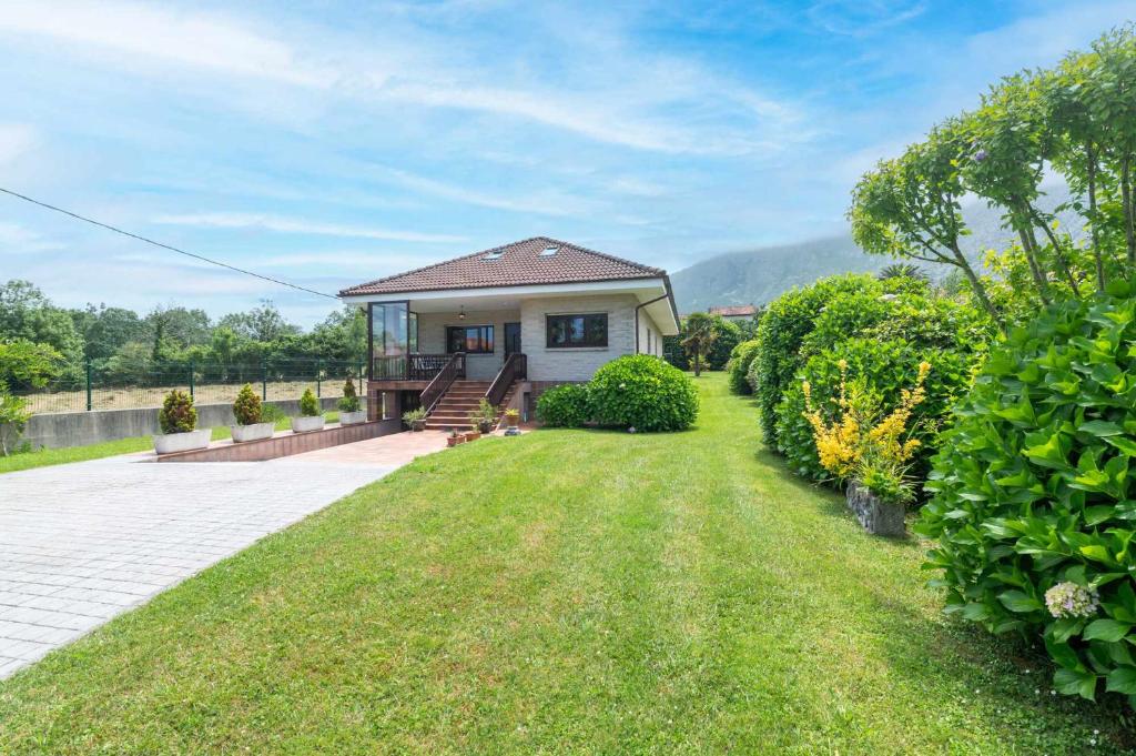 a small house with a grass yard at Casa Vacacional Carmina in Quintana de Llanes