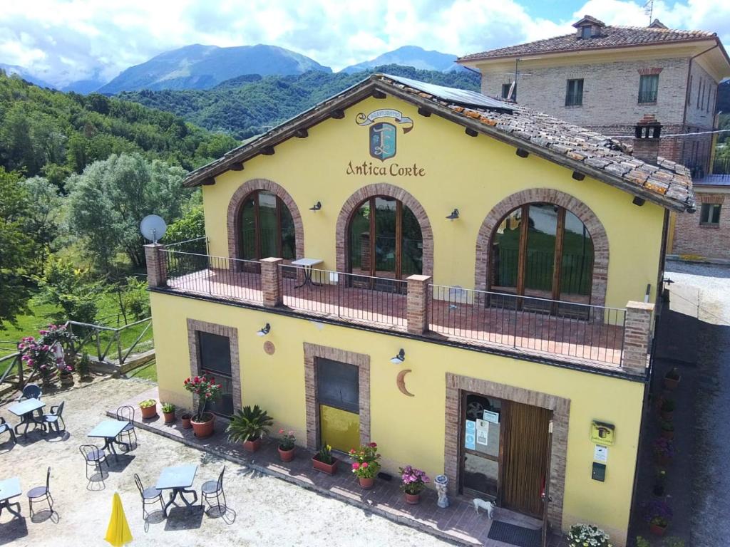 Montatteglia的住宿－Agriturismo Antica Corte，前面设有桌椅的黄色建筑