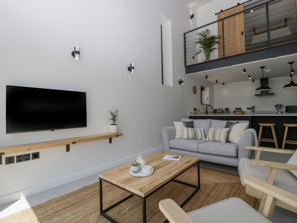 Una sala de estar con un sofá y un televisor en una pared. en Basswood Barn, en Wincanton