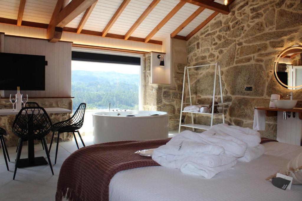 a bedroom with a tub and a bed with towels at Apartamentos Villa Maceira in Covelo