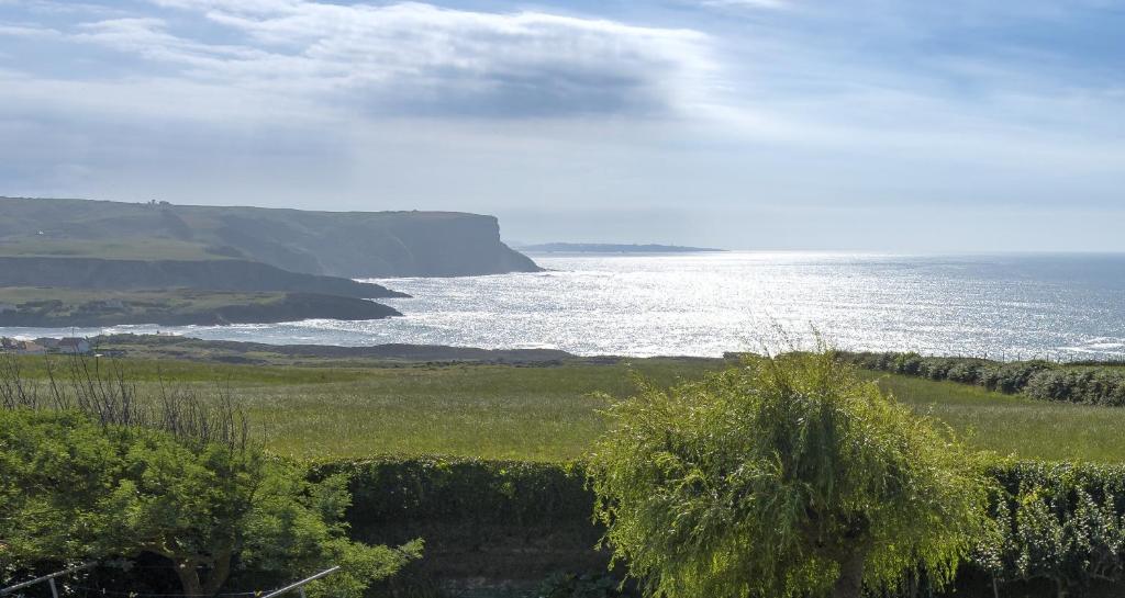 a view of the ocean from a field with a fence at La Casa del Faro de Ajo in Ajo