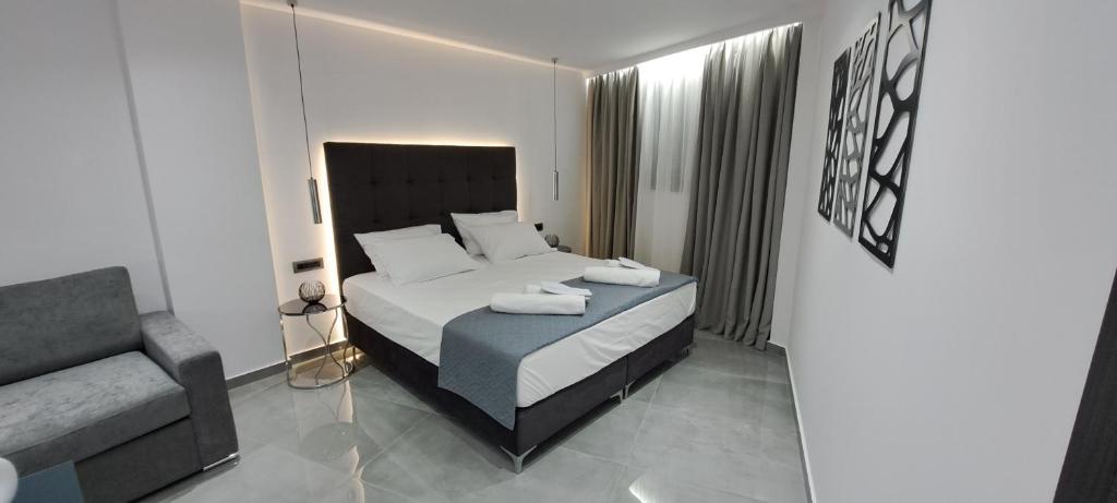 a bedroom with a bed with a chair and a couch at KM LUXURY APART DOWNTOWN in Heraklio Town