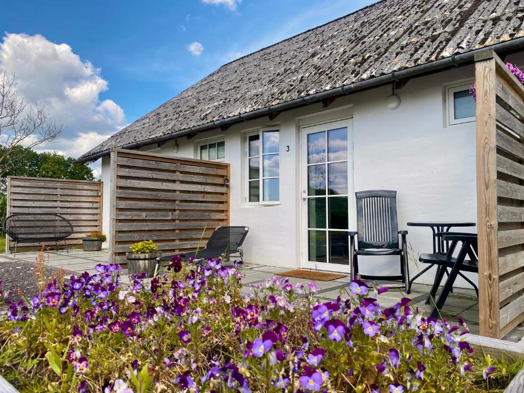 une maison avec une terrasse ornée de fleurs violettes dans l'établissement Bøgelund Sleep-in, à Karup