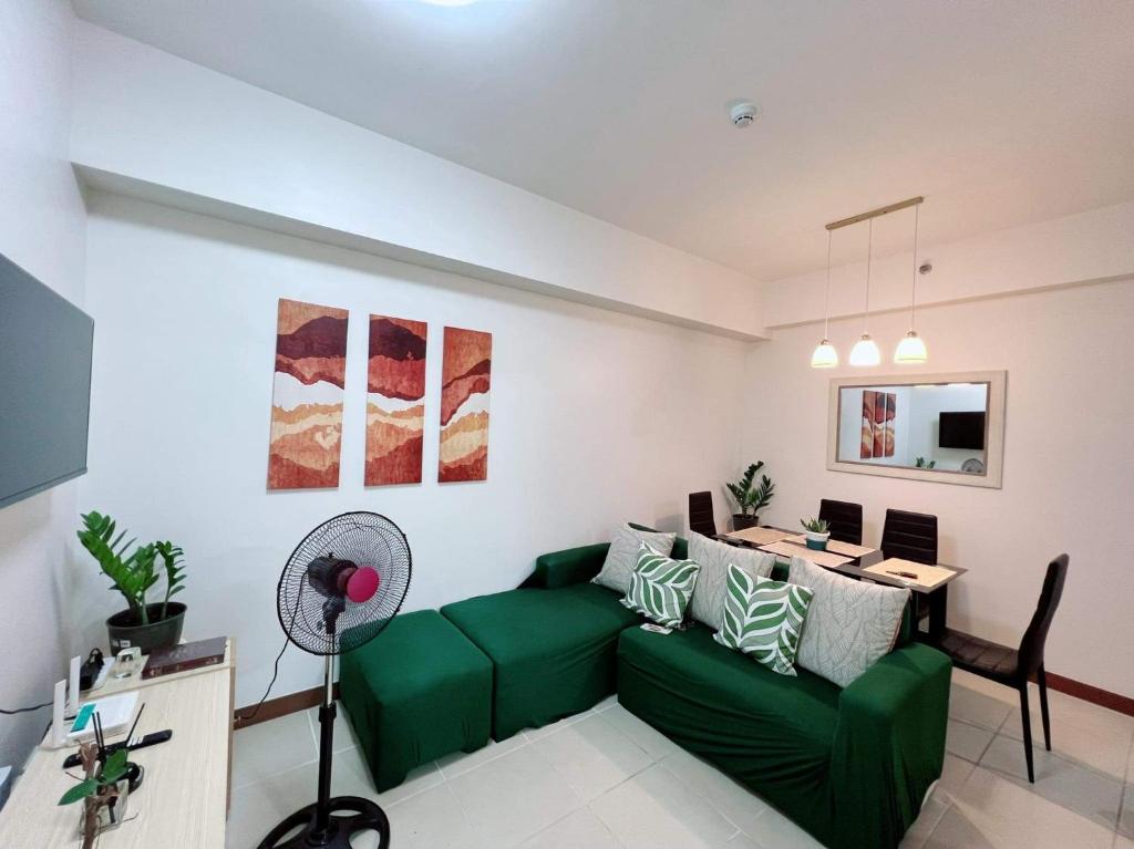 uma sala de estar com um sofá verde e uma mesa em Affordable 2BR with Terrace Shan Place Infina Tower-QC em Manila