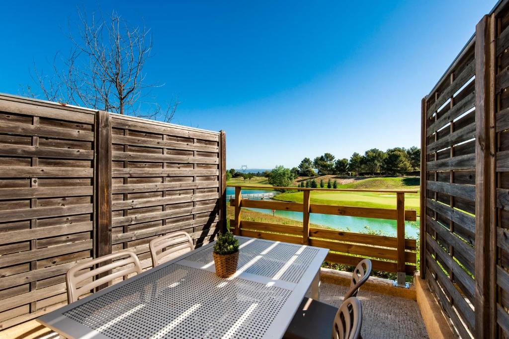 una mesa y sillas en un patio con una valla en La Cabre d'Or - Duplex avec piscine partagée en Cabriès