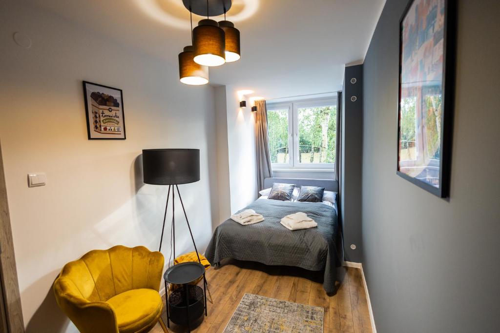 une petite chambre avec un lit et une chaise dans l'établissement Apartament Verde by Rentoom, à Toruń