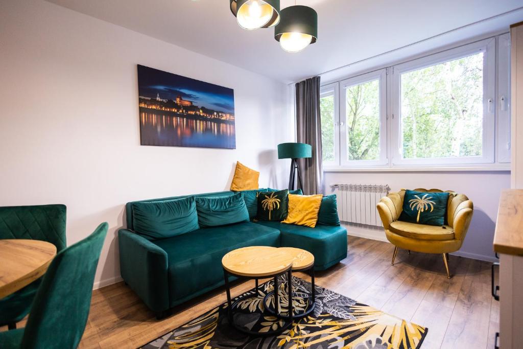 uma sala de estar com um sofá verde e uma mesa em Apartament Verde em Toruń
