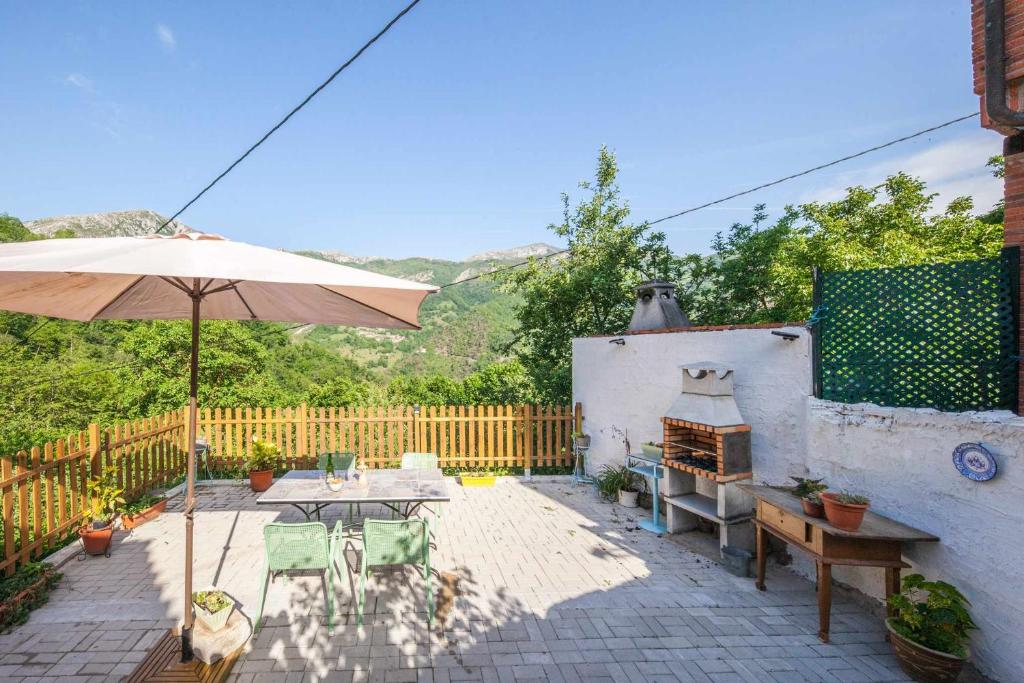 un patio con mesa y sombrilla en Carbayu Senda del Oso, en Proaza