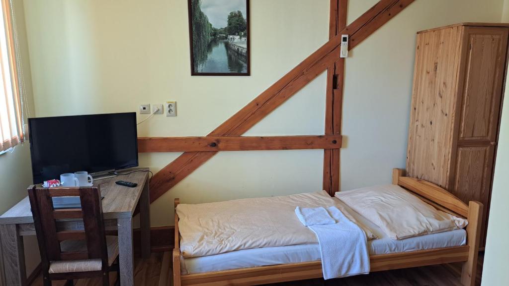 a room with a bed and a desk with a television at Penzion Bruder in Mojmírovce