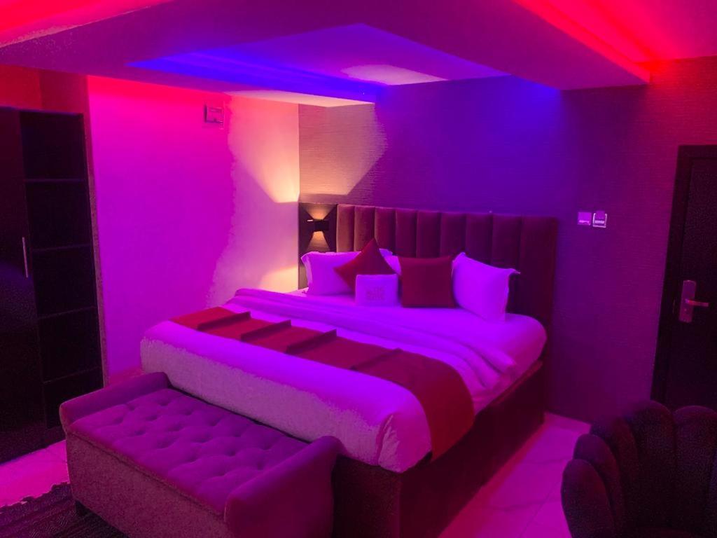 NO 95 SUITES VI في لاغوس: غرفة نوم أرجوانية مع سرير وأريكة
