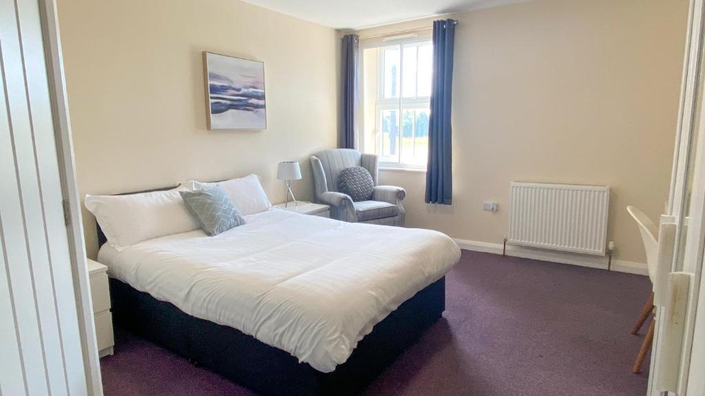 a bedroom with a bed and a chair in it at Bramall House Accommodation in Fewston