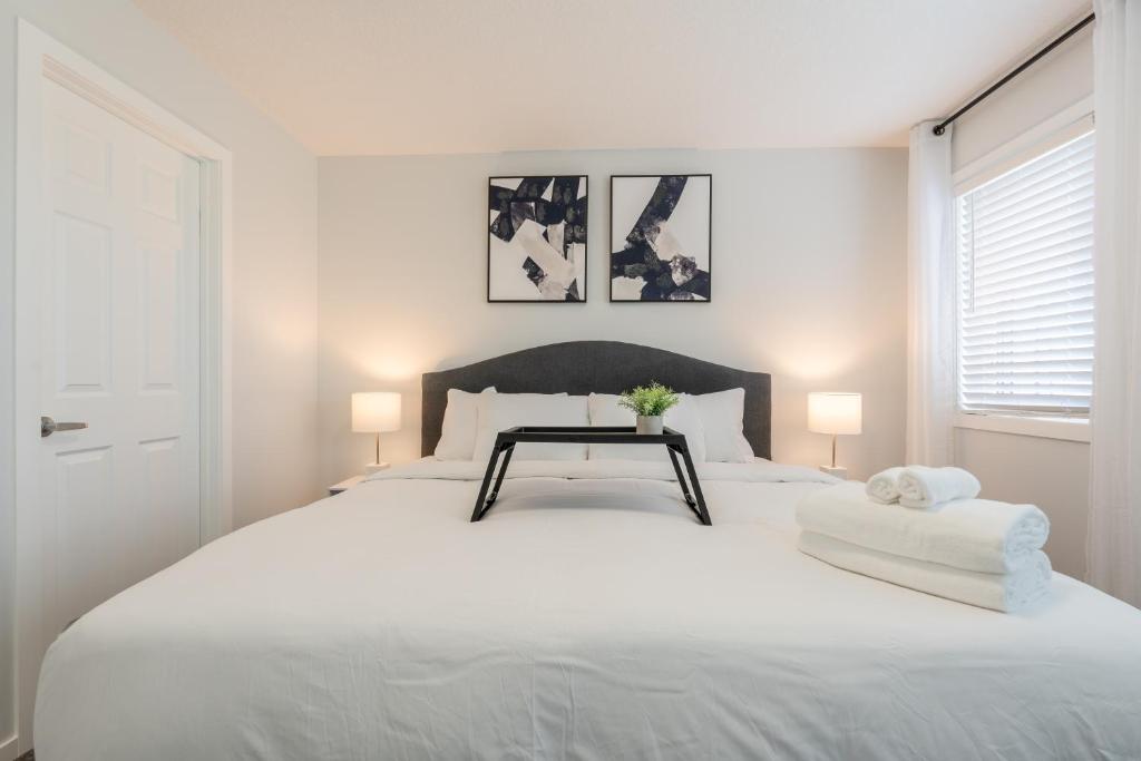 a white bedroom with a large white bed with two lamps at 3bedroom Stylish Getaway by the Park with 2-Car Garage in Calgary